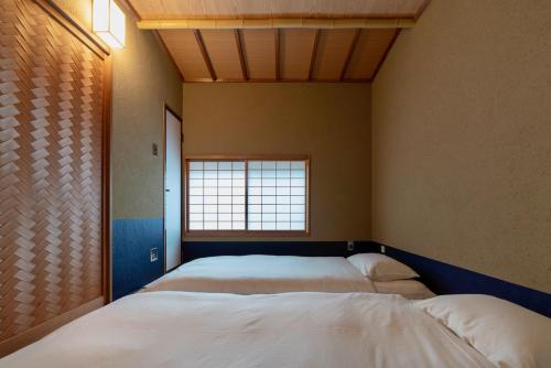 two beds in a room with a window at Hinaya Higashiyama Machiya House in Kanazawa