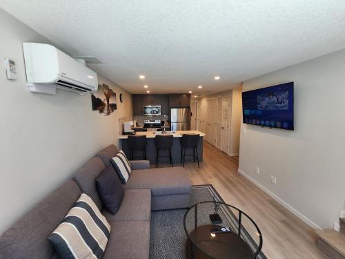 a living room with a couch and a kitchen at Cozy & Stylish AC Suite Near YYC Airport in Calgary