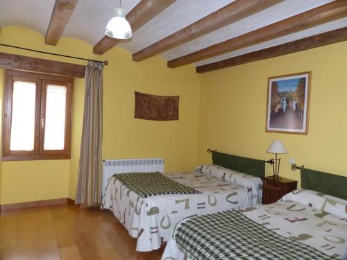 1 dormitorio con 2 camas y paredes amarillas en Casa Rural Iturrieta, en Adiós
