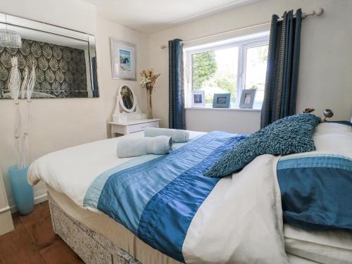 a bedroom with a bed with blue and white sheets at Delightful Dorset House By Wareham River in Wareham