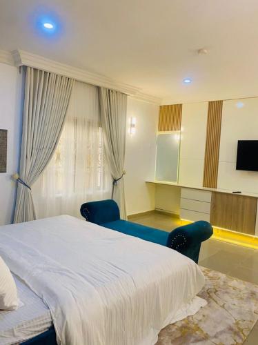 a bedroom with a bed and two chairs and a television at Games Village Suites and Apartments in Mama