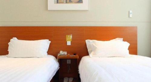 two beds in a hotel room with white pillows at Jinjiang Inn Style Shenyang The Palace Huaiyuan Gate in Shenyang