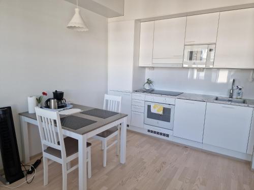 a kitchen with white cabinets and a table and chairs at New Center City Home in Kuopio