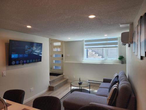 a living room with a couch and a tv on a wall at Cozy & Stylish AC Suite Near YYC Airport in Calgary