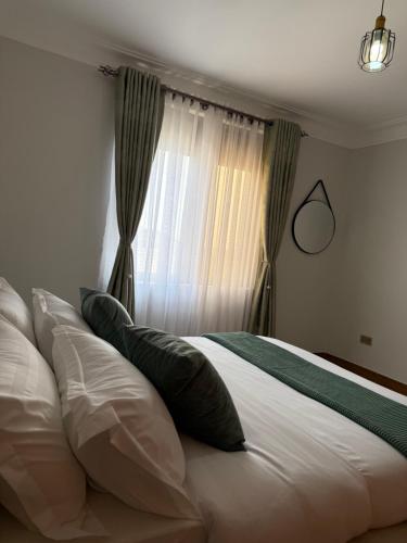 a bed with pillows in front of a window at Jasmine Homes in Kampala