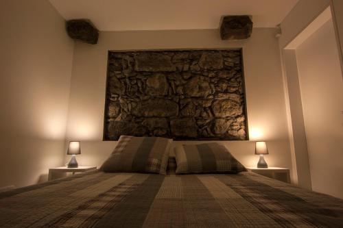 a bedroom with a large stone wall above a bed at Casa do Simão in Nordeste