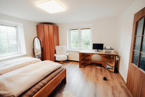 a bedroom with a bed and a desk with a computer at Chalupa na konci cesty 