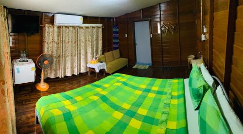 a bedroom with a green and yellow bed and a couch at Banthai Guesthouse in Phetchaburi
