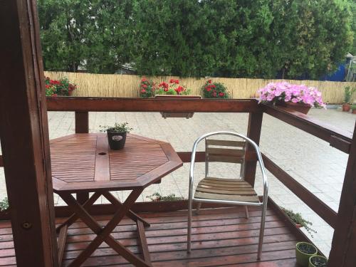 a wooden table and a chair on a deck with flowers at Abszolút Hotel és Panzió in Nyírbátor