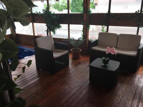 a porch with two chairs and a table and plants at Abszolút Hotel és Panzió in Nyírbátor