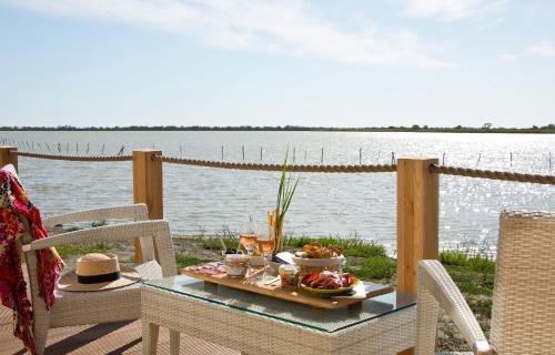 a table with a tray of food on a deck overlooking the water at Lodge Sainte Helene Adult only in Saintes-Maries-de-la-Mer