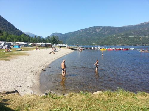 a man and a child standing in the water at a beach at Garvikstrondi Camping in Seljord