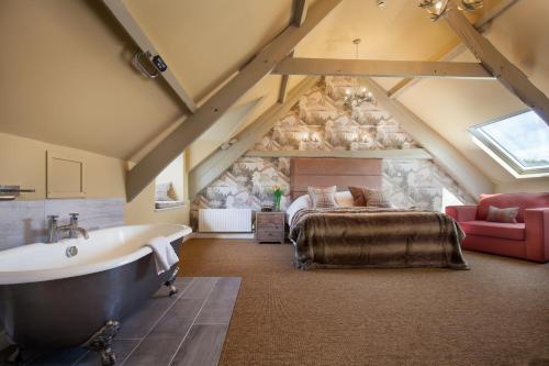 uma casa de banho no sótão com uma banheira e uma cama em Mill End Hotel em Chagford