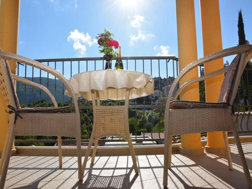 a table and chairs on a balcony with a vase of flowers at Apartmani Niksic in Herceg-Novi