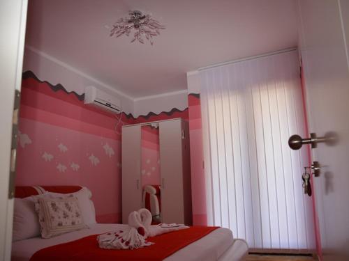 a bedroom with a bed with a pink wall at Apartmani Niksic in Herceg-Novi