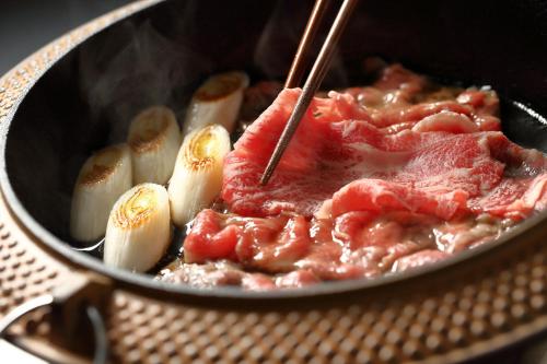 a pot of food with meat and vegetables in it at Ooedo Onsen Monogatari Awazu Grand Hotel in Komatsu