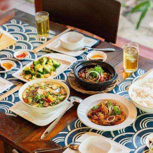 a wooden table with plates of food on it at HON BA LAGI BEACH RESORT in La Gi