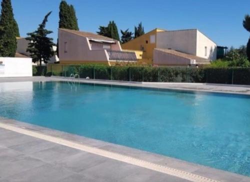 une grande piscine bleue devant un immeuble dans l'établissement Tennis Village appartement calme et confort, au Cap d'Agde