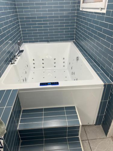 eine Badewanne in einem blau gefliesten Bad in der Unterkunft Maison vacances in Saint-Mammès