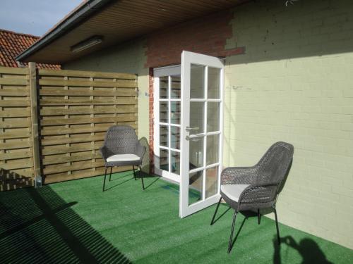 two chairs and a door on a patio at B&B De Zoete Kers in Wakken