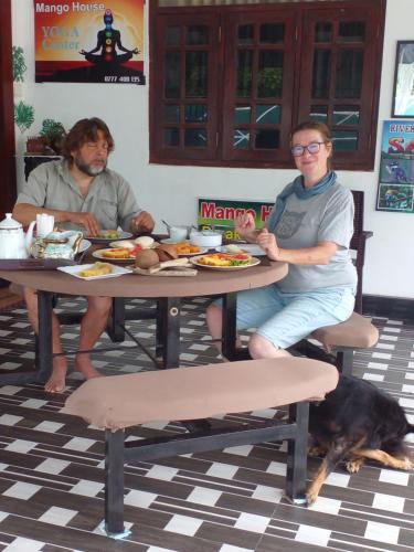 a man and a woman sitting at a table with a dog at Mango House River Inn Negombo in Kochchikade
