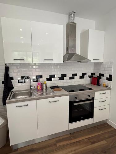 a white kitchen with a sink and a stove at Domaine Baccia Donna Proche Nice, Climatisation, Jacuzzi chauffé, Pétanque & Parking gratuit in La Trinité