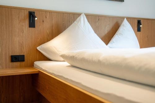 a bed with white pillows on a boat at Hotel Garni Krumbach in Damuls