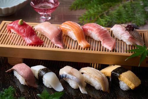 a bunch of sushi on a wooden tray at Ooedo Onsen Monogatari Hotel Ranpu in Hirado