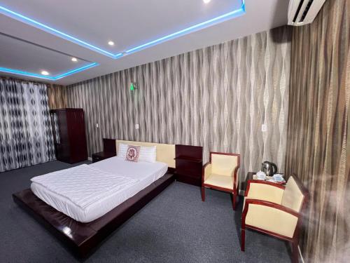 a bedroom with a bed and two chairs in it at Khách sạn phi long 2 in Ấp Phú Thọ