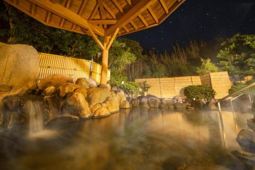 a stream of water with rocks and a roof at Ooedo Onsen Monogatari Hotel Ranpu in Hirado