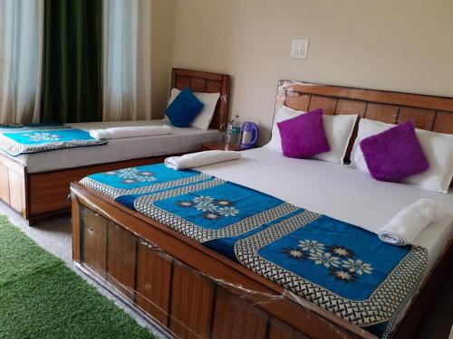 two beds in a room with purple and blue pillows at Vijay Residency in Barkot