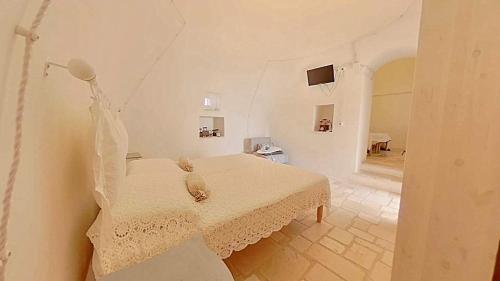 a white room with a bed and a table at i trulli di Holly in Selva di Fasano