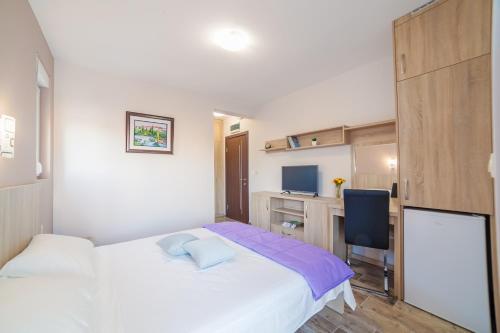 a bedroom with a white bed and a desk at Milara Apartments in Budva