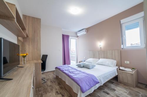 a bedroom with a large bed and a flat screen tv at Milara Apartments in Budva