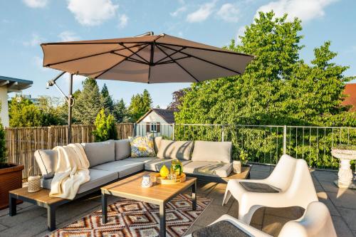 a patio with a couch and an umbrella at LubuNest3 Terrasse mit Grill & eigenem Parkplatz in Ludwigsburg