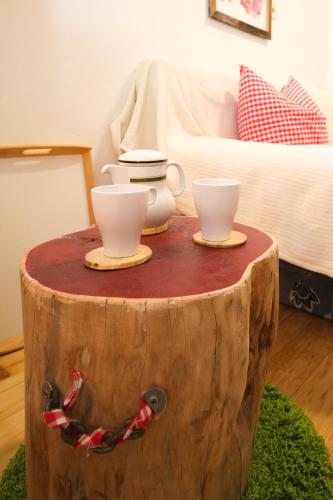 a table made out of a tree stump with two cups on it at Oberachen Apartment in Ellmau