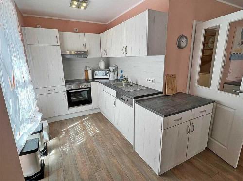 a kitchen with white cabinets and a counter top at Ferienhaus Meiereikoppel 11 in Bannesdorf