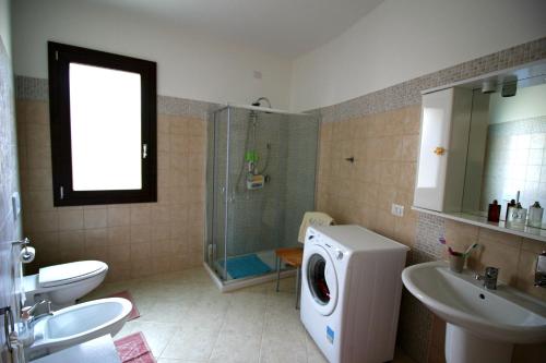 a bathroom with a shower sink and a washing machine at Naracauli in Arbus