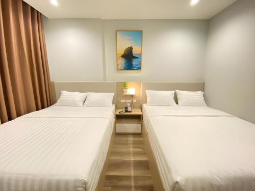 two twin beds in a room with a table at Vũ Gia Phú Quốc Hotel in Phu Quoc