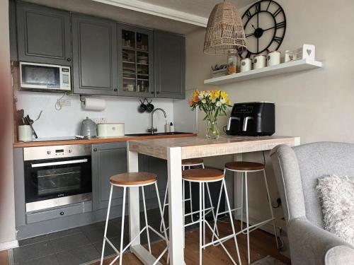 a kitchen with gray cabinets and a counter with stools at 2 Bedroom Harbour Apartment in Porthmadog
