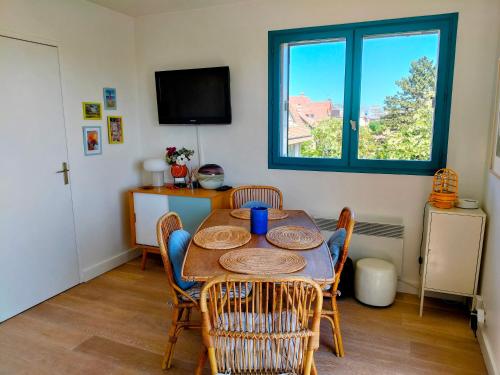 une salle à manger avec une table et des chaises et une fenêtre dans l'établissement Charmant Appartement proche mer et centre, calme, 4 pers, à Cabourg