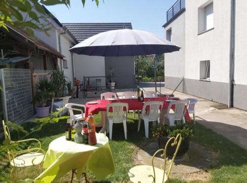 un tavolo rosso e sedie sotto un ombrellone di Chez Jeanine Maison Familiale a Schaeffersheim