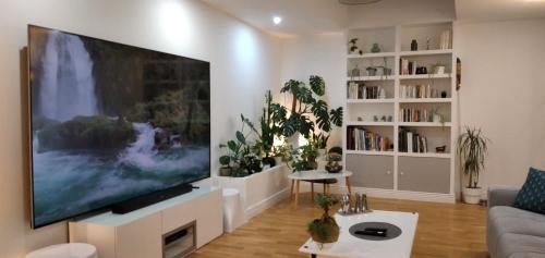 un salon avec une grande télévision à écran plat sur un mur dans l'établissement Expérience Inouïe à Orléans !, à Orléans