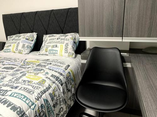 a black chair sitting next to a bed in a room at Mini Apartment in Lima