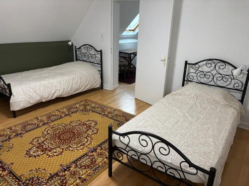 Un dormitorio con dos camas y una alfombra. en Maison 4 Chambres Normandie, en Clasville