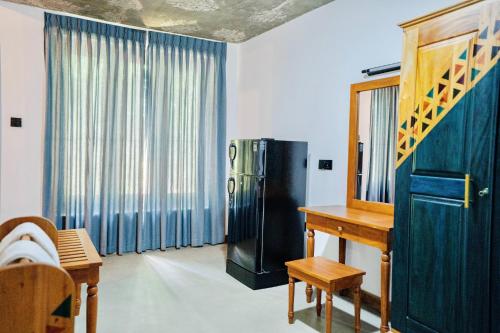 a room with a refrigerator and a table and a mirror at Muthu Nila villas- Mirissa in Mirissa