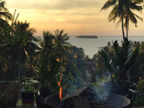 a fire pit with palm trees and the ocean at Querencia Siargao 