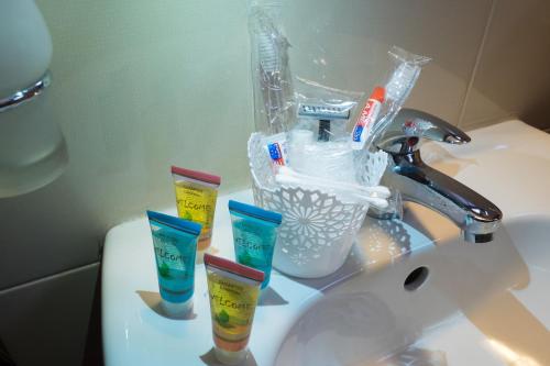 a bathroom sink with toothbrushes and cups on it at City Blagoevgrad Family Hotel in Blagoevgrad