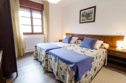 1 dormitorio con cama con sábanas azules y ventana en HOTEL-APARTAMENTOS LA BILBAINA, en Vegadeo