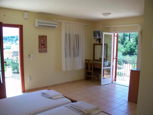 a bedroom with a bed and a desk and a balcony at Rosa's Studios in Fiskardo